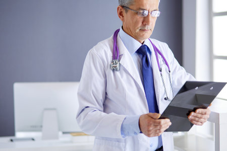 Male doctor writes notes on the clipboard in the hospitalの写真素材