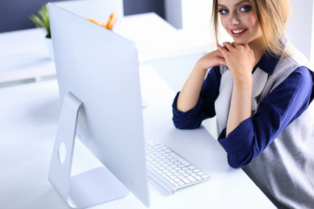 Young confident businesswoman working at office desk and typing with a laptopの写真素材