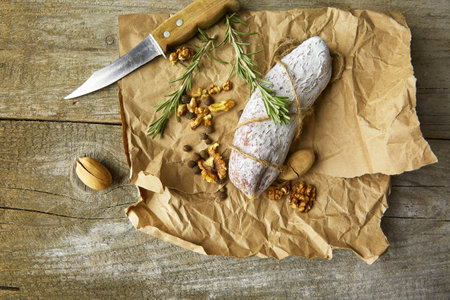 Italian salami wih sea salt, rosemary, garlic and nuts on paper. Rustic style. Close up.の写真素材