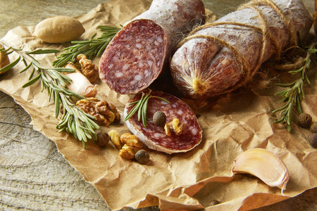 Italian salami wih sea salt, rosemary, garlic and nuts on paper. Rustic style. Close up.の写真素材