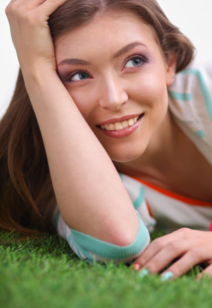 Beautiful young woman lying on the green grassの写真素材