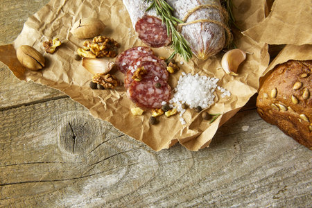 French salami and walnuts on craft paper on wooden backgroundの写真素材