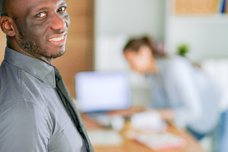 Attractive woman sitting at desk in office having takeaway coffee.の写真素材