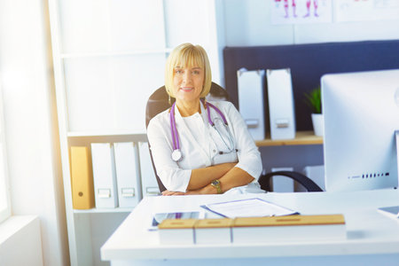 Portrait of young woman doctor in white coat at computerの写真素材