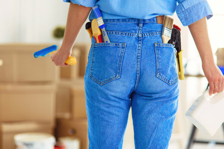 Pretty smilling woman painting interior wall of home with paint rollerの写真素材