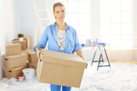 Young woman moving house to new home holding cardboard boxesの写真素材