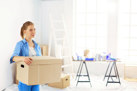 Young woman moving house to new home holding cardboard boxesの写真素材