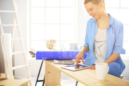 Young woman sitting at home and buying new furniture over the Internet using a tablet computerの写真素材