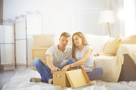 Couple in new home between the boxes, with a Tablet PC in the handsの写真素材