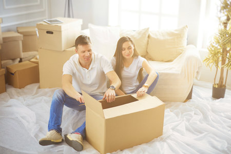 Happy young couple unpacking or packing boxes and moving into a new homeの写真素材