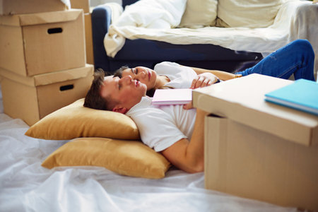 High view of happy couple lying on floor with a lot of boxesの写真素材