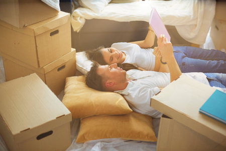 High view of happy couple lying on floor with a lot of boxesの写真素材