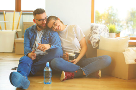 Happy couple planning decoration when moving home sitting on the floorの写真素材