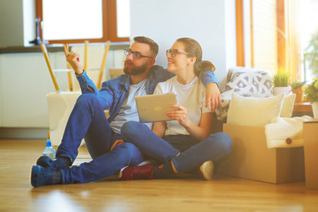 Happy couple planning decoration when moving home sitting on the floorの写真素材