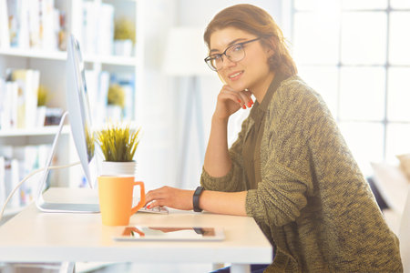Happy woman working using multiple devices on a desk at homeの写真素材