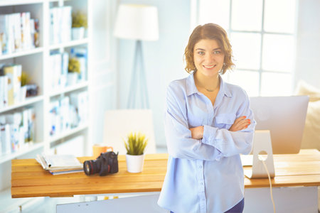 Portrait of smiling young woman with dslr photo camera standing in loft apartmentの写真素材