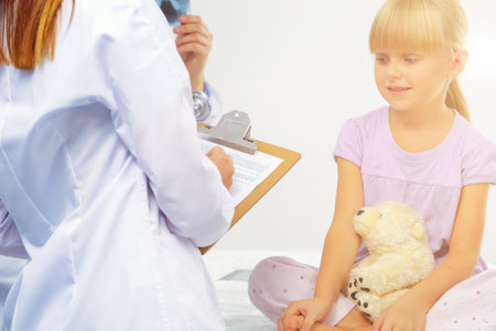Female doctor examining child with stethoscope at surgeryの写真素材