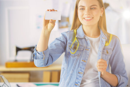 Beautiful young woman designer with business card in officeの写真素材