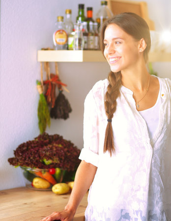 Young woman standing near desk in the kitchen. Young woman .の写真素材