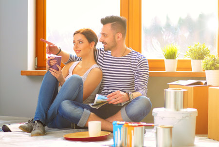 Portrait happy smiling young couple painting interior wall of new house. Young coupleの写真素材