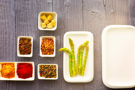 Fresh asparagus served on white plate with rustic wooden table background, top view.の写真素材