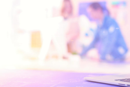 Two young woman standing near desk with instruments, plan and laptop.の写真素材