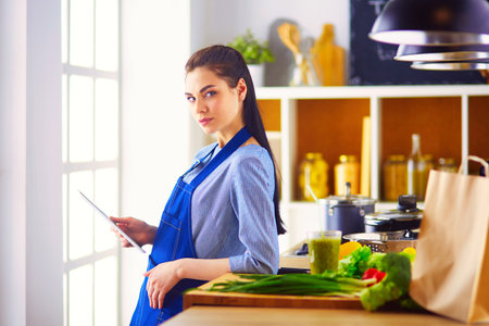 Young woman using a tablet computer to cook in her kitchenの写真素材