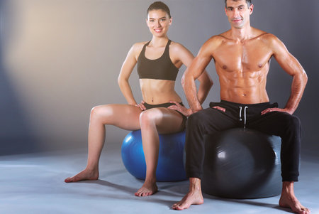 Two smiling people with fitness ball in the gym. Personal fitness instructor. Personal training. Gym workout.の写真素材