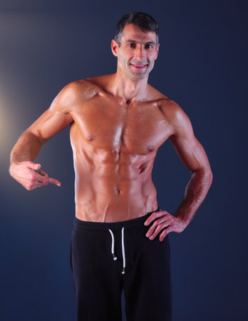 muscular man. Muscular man on a grey background showing muscles. Fitness instructor. Fitness professional. Workout. Mens fitness.の写真素材