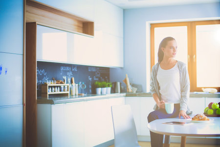 Happy woman drinking tea in the kitchen at home.の写真素材