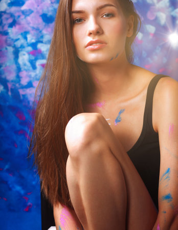 Young woman sitting near painting wallの写真素材