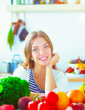 Young woman standing near desk in the kitchen. Young woman .の写真素材