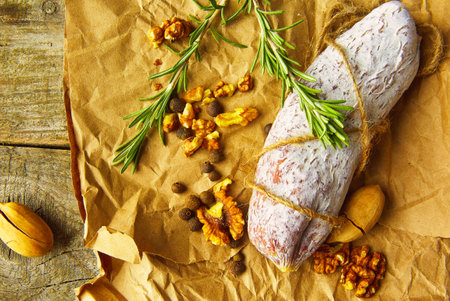 Italian salami wih sea salt, rosemary, garlic and nuts on paper. Rustic style. Top view.の写真素材