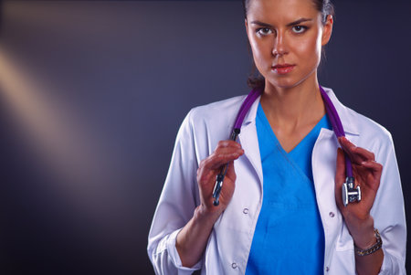 Portrait of young female doctor holding a stethoscope, isolated on black backgroundの写真素材
