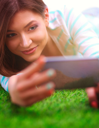 Beautiful young woman lying on green grassの写真素材