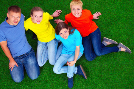 Group of young people sitting on green grassの写真素材