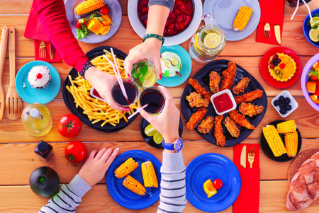 Top view of group of people having dinner together while sitting at wooden table. Food on the table. People eat fast food.の写真素材