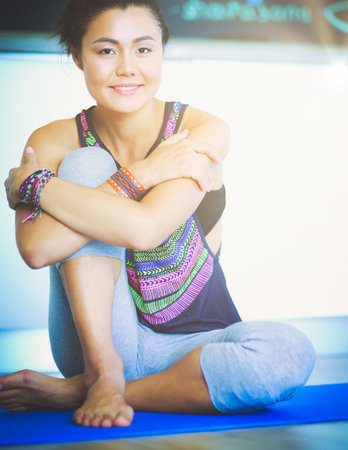 Portrait of smiling yoga woman sitting at yoga mat after workout at yoga studio. Yoga. Woman.の写真素材