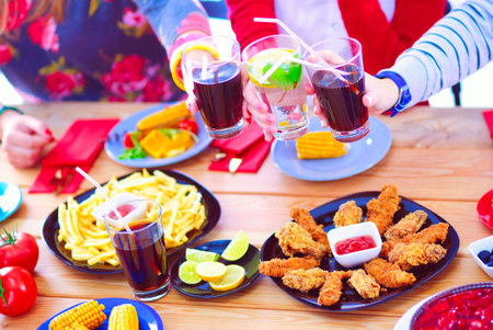 Top view of group of people having dinner together while sitting at wooden table. Food on the table. People eat fast food.の写真素材