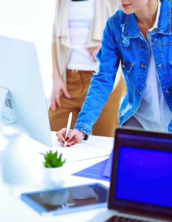 Two young woman standing near desk with instruments, plan and laptop.の写真素材
