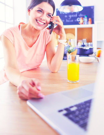 Young woman in kitchen with laptop computer looking recipes, smiling. Food blogger conceptの写真素材