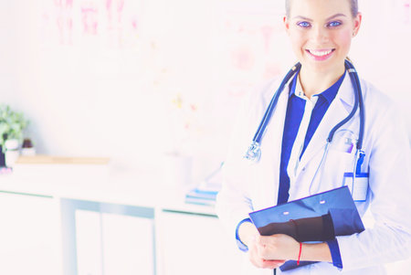Smiling female doctor with a folder in uniform standingの写真素材