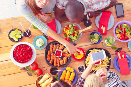 Top view of group of people having dinner together while sitting at wooden table. Food on the table. People eat fast food.の写真素材