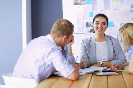 Young people studying with books on desk. Beautiful women and men working together.の写真素材