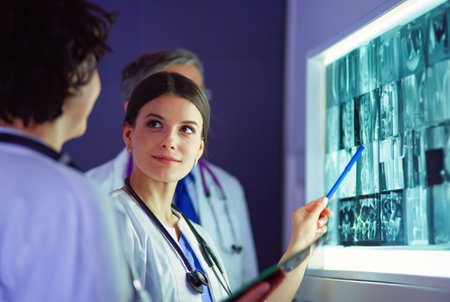Group of doctors examining x-rays in a clinic, thinking of a diagnosisの写真素材