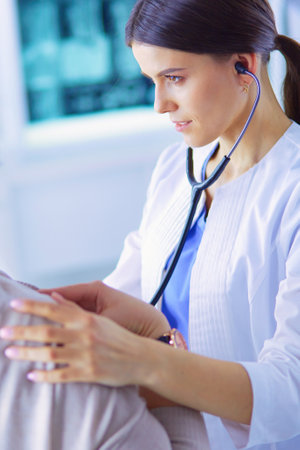 A female doctor listening a patient with a stethoscopeの写真素材