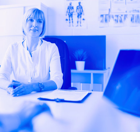 Couple talking to medical specialist, sitting at doctors officeの写真素材