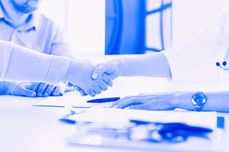 Woman doctor handshaking with a senior coupleの写真素材