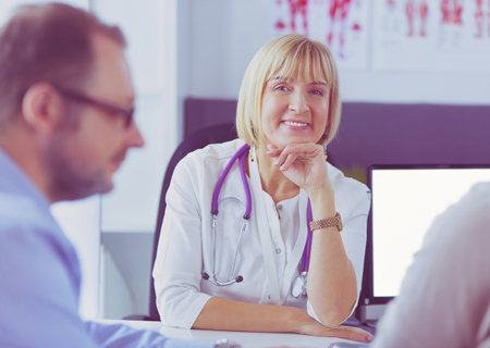 Attentive senior doctor listenint to patient in her officeの写真素材