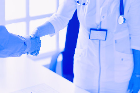 Female doctor handshaking a patients hand and smilingの写真素材
